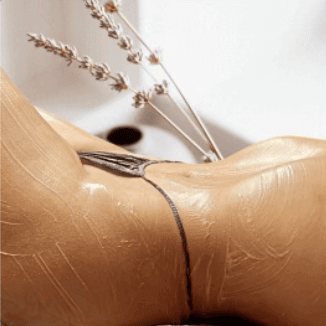 Sculpted Beauty client's torso, laying down face up with a black thong and product on the skin